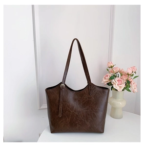 Close-up of retro dark brown tote bag with oily leather texture and metal buckle detail