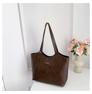 Detail of dark brown tote bag with vintage texture and gold fashion logo branding