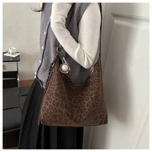 Close-up of leopard print tote bag featuring a decorative baseball bat charm and strap