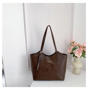 Close-up of retro dark brown tote bag with gold logo text and smooth leather texture