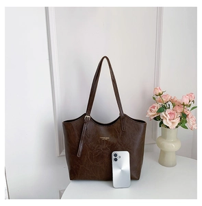 Detailed close-up of dark brown tote bag texture with gold fashion lettering and shoulder strap