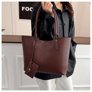 Large brown leather tote bag detail with matching mini envelope pouch for daily commuting