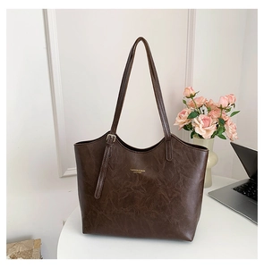 Close-up of brown faux leather tote bag with gold lettering and metallic buckle detail
