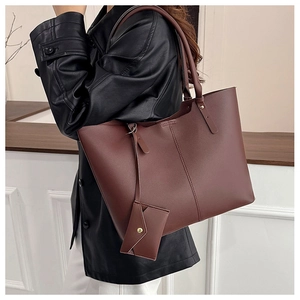 Detail of burgundy leather tote bag with vertical stitching and matching small pouch