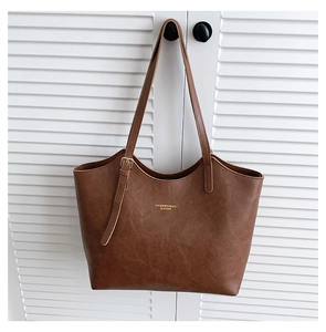 Detail of brown faux leather tote with golden logo and smooth vintage texture