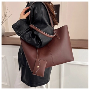 Detail view of large dark brown tote bag set with a matching envelope charm on a model