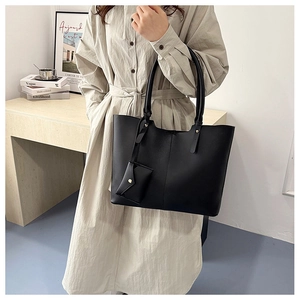 Detail of minimalist black leather tote bag with gold hardware and matching mini pouch