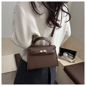 Brown litchi leather mini handbag showing scale and texture on a female model