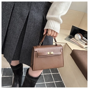 Detail of dark brown crossgrain leather trapezoid handbag with gold rotating clasp buckle