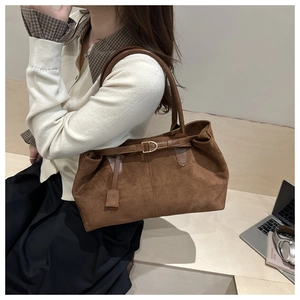 Detail of brown faux suede tote bag featuring sleek leather straps and metal buckle accents