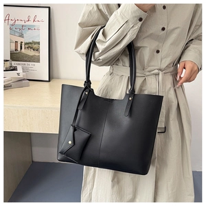 Detail of minimalist black tote bag with long straps and attached mini envelope pouch