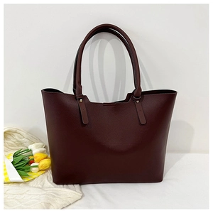 Detail of burgundy tote bag showing large capacity, metallic hardware, and smooth texture