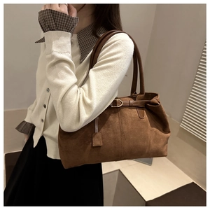 Detail of a vintage dark brown suede tote bag featuring a metallic buckle and soft texture