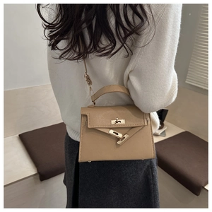 Detailed side view of khaki trapezoid leather handbag with metal turn-lock and strap