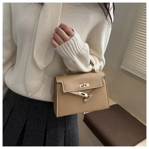 Detail of vintage khaki leather handbag featuring golden twist lock and belt buckle design