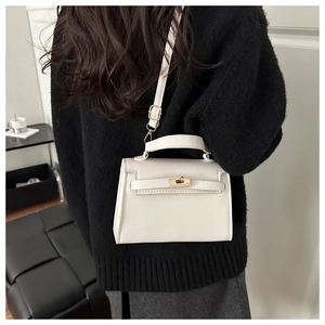Detail of white lychee texture leather handbag with gold metal clasp on a model