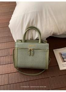 Detail of green retro handbag with herringbone weave pattern and gold logo plaque