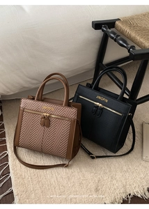 Close-up of vintage brown woven leather tote and sleek black shoulder bag on a soft beige rug