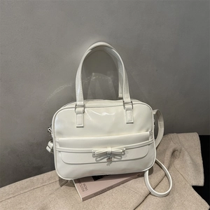 White faux leather large tote bag with bow detail and heart pendant on pink books
