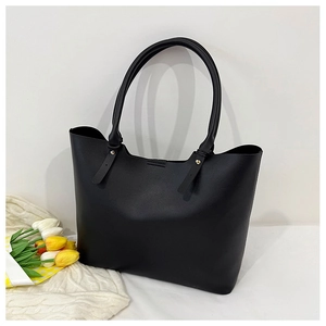 Detail view of large black tote bag with fine stitching and metal rivet fasteners