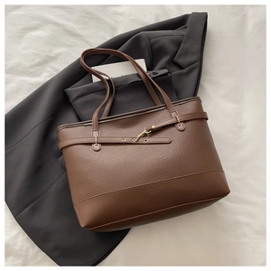 Detail of brown litchi grain tote bag with decorative buckle straps and gold hardware