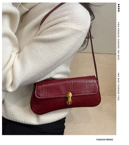 Detail of burgundy crocodile pattern leather texture with a gold metal clasp lock