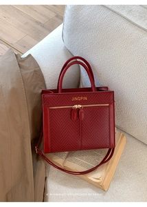Detail of red woven tote bag with golden lettering on premium faux leather surface
