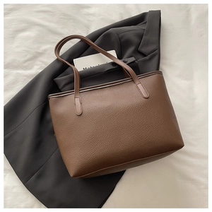 Macro detail of brown lychee-patterned leather tote bag showing rich texture and stitching