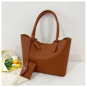 Detail of a large brown tote bag with smooth texture and matching pendant accessory