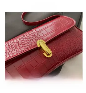 Detail of red crocodile embossed leather underarm bag with gold metal buckle clasp