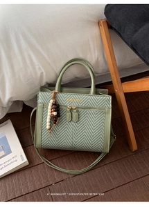 Detail of green weave tote bag featuring ethnic wooden bead charm and long shoulder strap