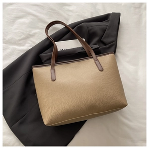 Detailed macro view of the beige lychee texture leather tote bag with brown trim