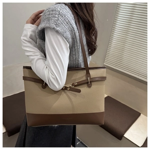 Detail of a color-block tote bag with lychee texture and gold buckle on shoulder
