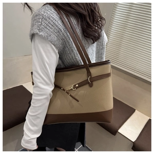 Detail of large contrast tote bag in litchi leather worn on shoulder by model
