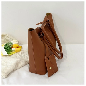 Detail of caramel brown leather tote bag with matching envelope pouch on white decor