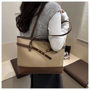 Detail of a large tote bag featuring contrast leather textures in a professional office setting