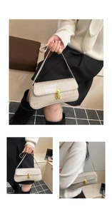 Detailed view of cream baguette bag with crocodile texture and gold metal clasp