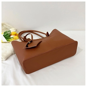 Top-down view of a dark brown large tote bag on white fabric with tulips and a cozy blanket