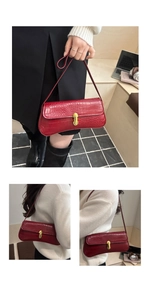 Close-up of deep red crocodile embossed texture and golden capsule lock on underarm bag