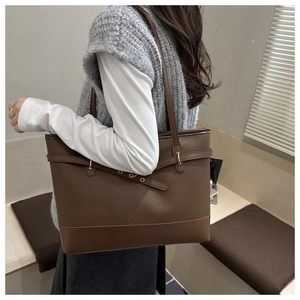 Detailed side view of a brown leather tote bag with stylish metal rings and textured finish