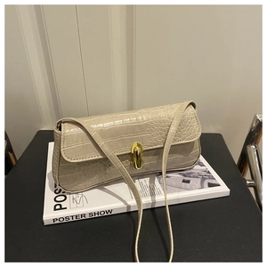Detail of cream faux crocodile texture and gold oval clasp on a small baguette bag