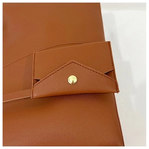Detailed close-up of brown leather texture and gold magnetic buckle on shoulder bag
