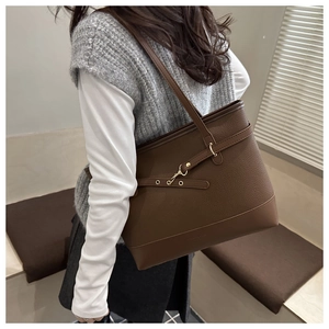 Detail of dark brown tote bag featuring lychee grain leather and golden metal buckle