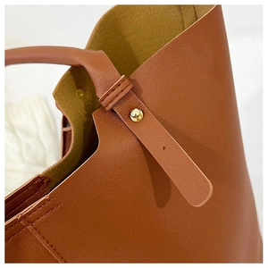 Close-up of caramel leather shoulder bag with lychee texture and gold rivet details