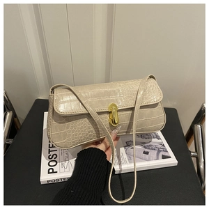 Detail of beige crocodile pattern bag with golden lock on a magazine