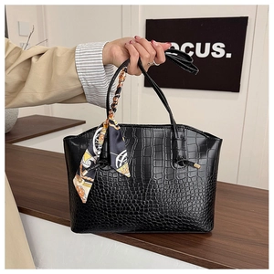 Detail of black crocodile pattern tote bag with decorative silk scarf on the handle