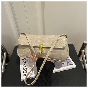 Detail showing beige croc-embossed texture and golden U-shaped buckle on baguette bag