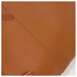 Detailed close-up of premium brown leather texture with precise stitching on a tote bag
