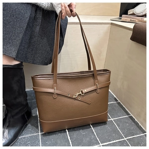 Detail of brown litchi pattern leather tote bag with gold buckle and logo embossing