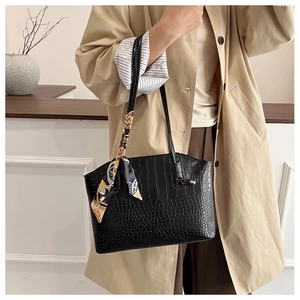 Detail of black tote bag featuring crocodile embossed texture and decorative silk scarf